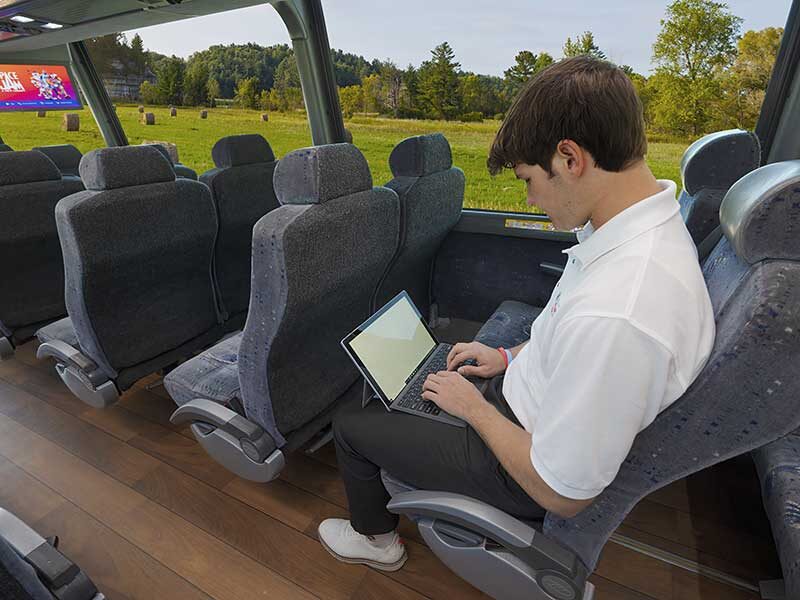 Man sitting in bus using his laptop computer