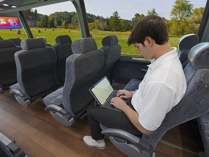 Man sitting in Heartland Trailways bus using his laptop computer